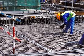 Steel-fixer bending over and tying without the rebar tie machine. 